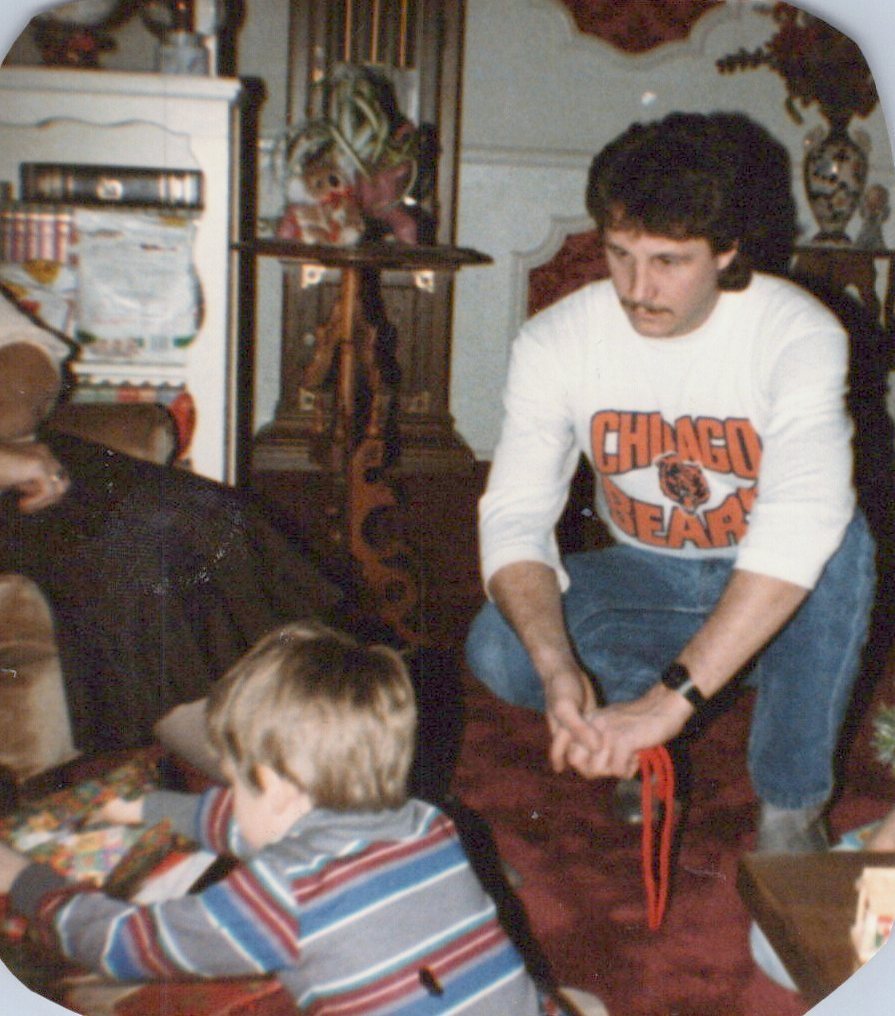 Mike in a Chicago Bears sweatshirt kneeling beside young Shane